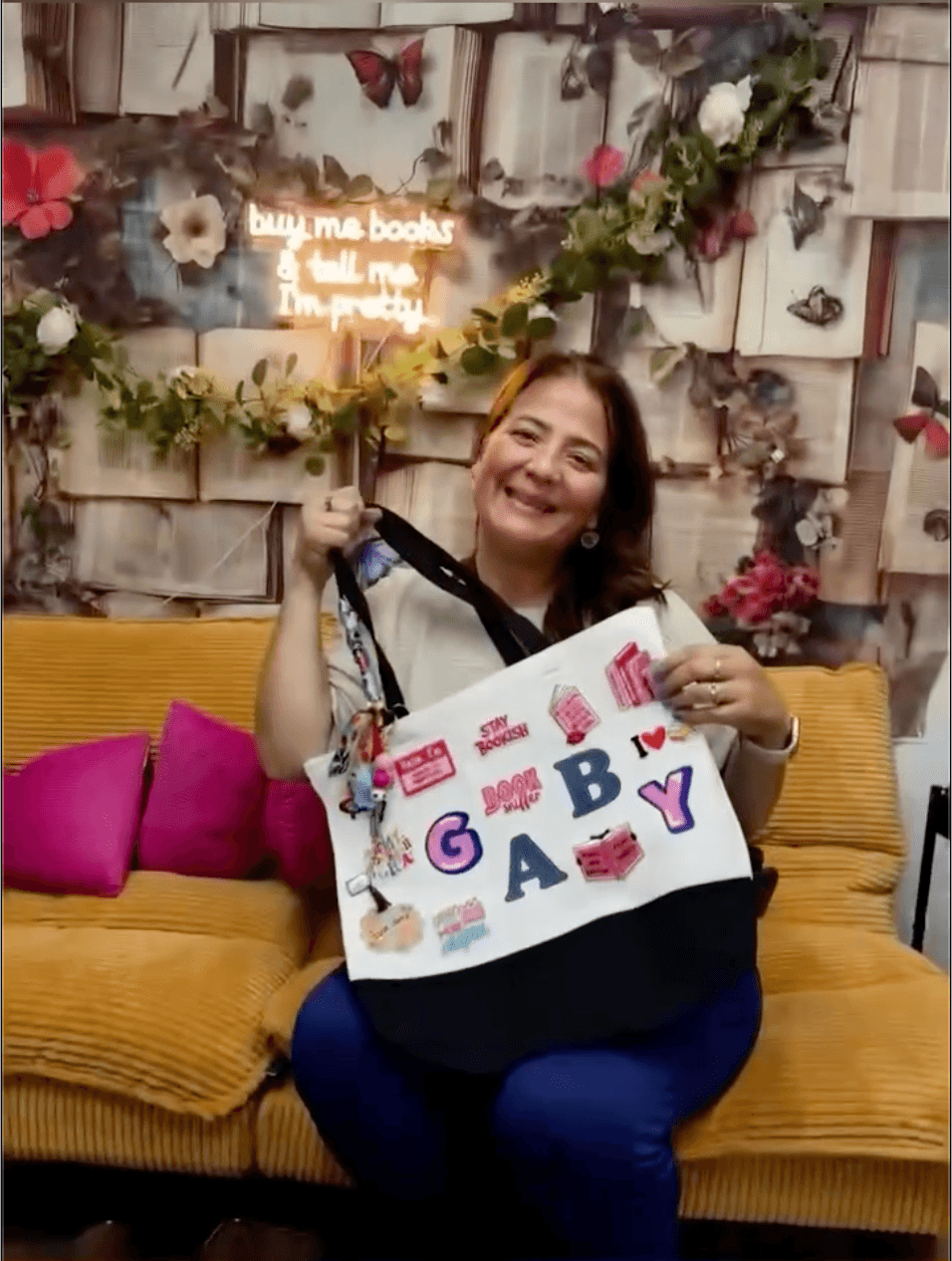 A smiling maker at Twists & Tales holding her finished bookish tote covered in colorful patches.