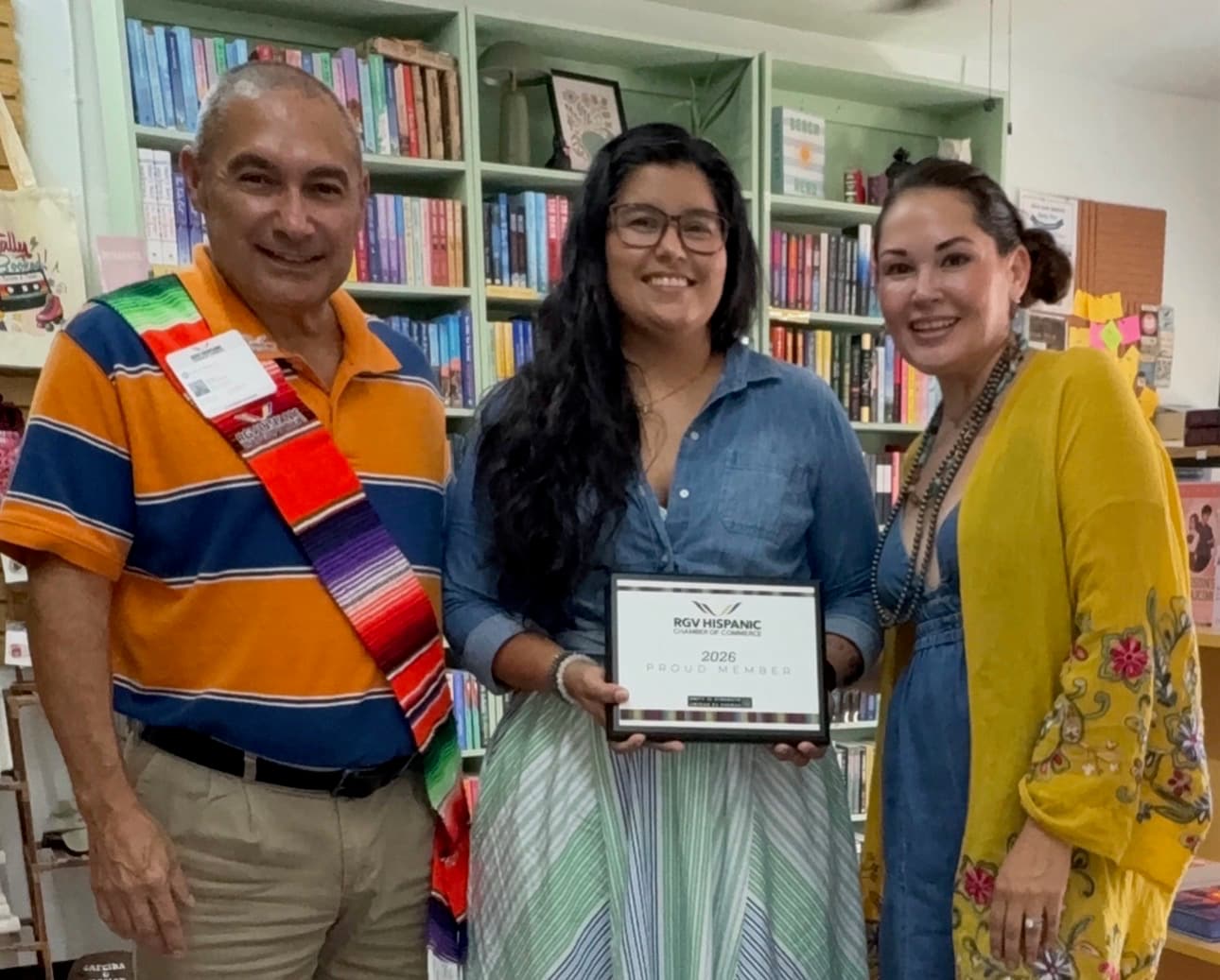 The Twists & Tales owners with an RGV Hispanic Chamber representative inside the bookshop, holding their new member certificate.